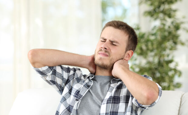 Man suffering neck pain at home